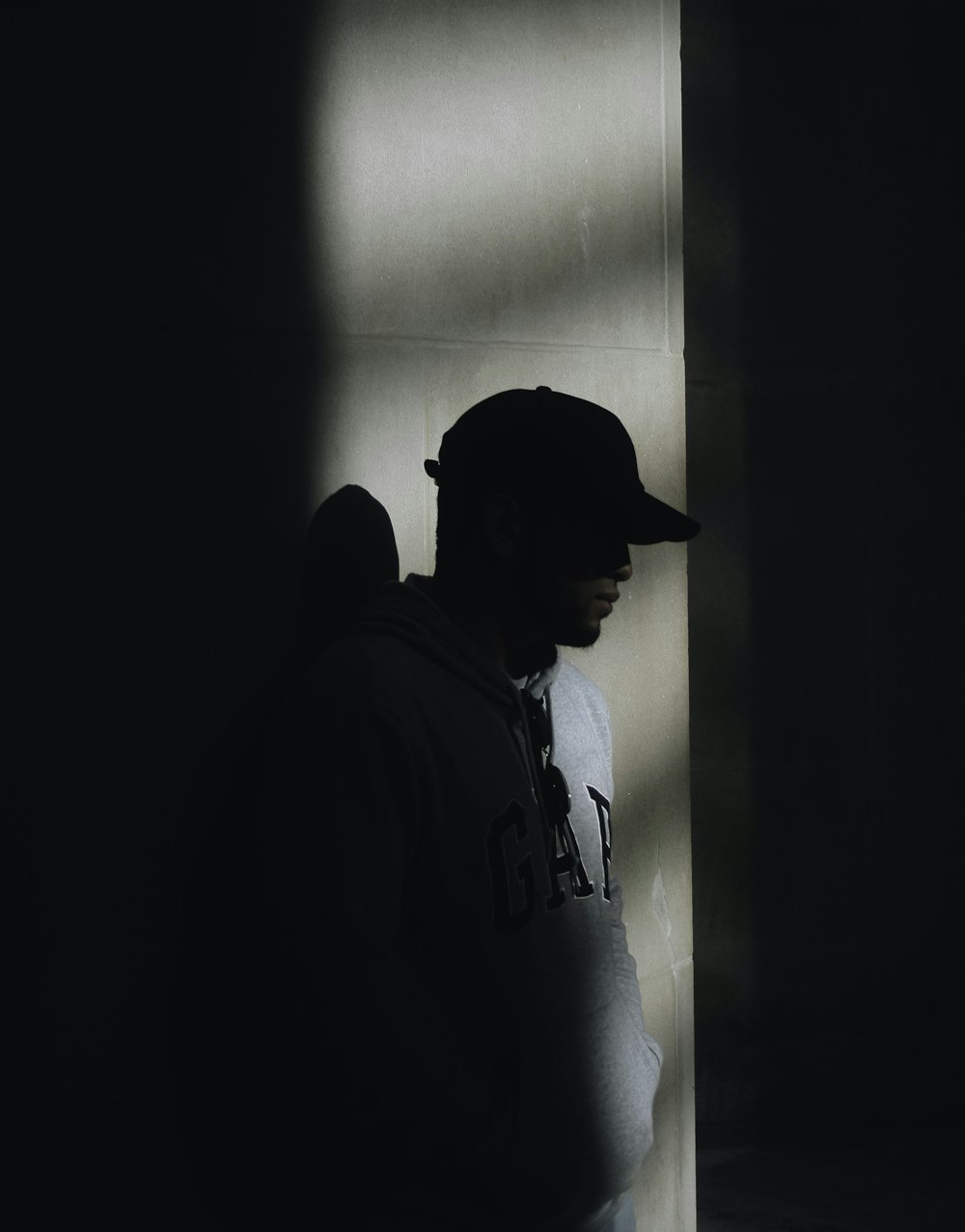 man in gray Gap hoodie standing on dark place