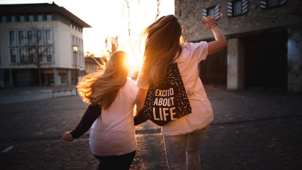 two women walking across the road during sunset