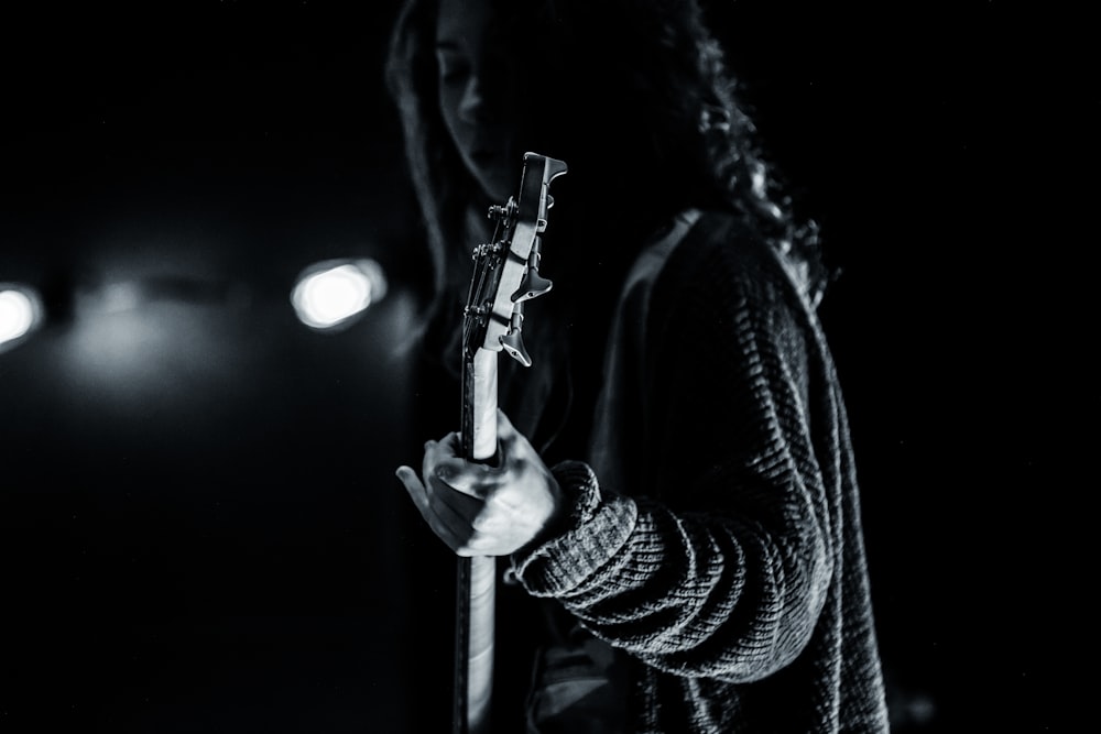 fotografia em tons de cinza da pessoa tocando guitarra