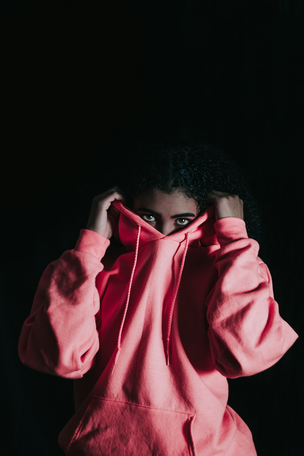 chica con sudadera con capucha rosa que cubre su nariz