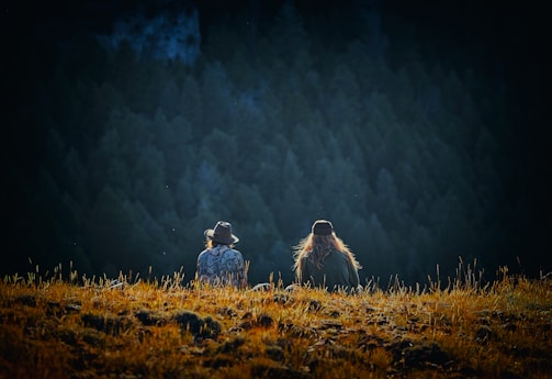 man and woman sitting on brown field