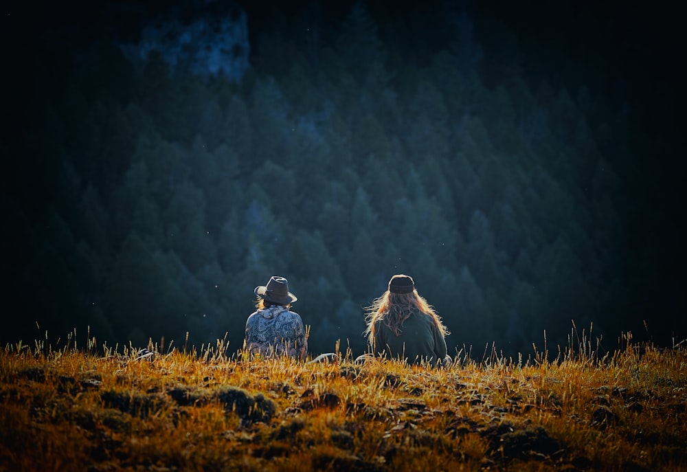 man and woman sitting on brown field