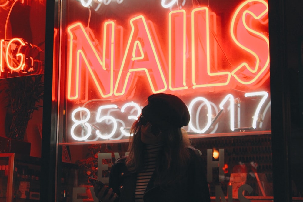 a woman standing in front of a neon sign