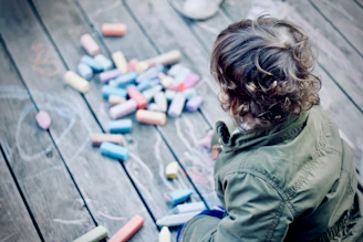 child sitting in front of assorted-color chalk drawing