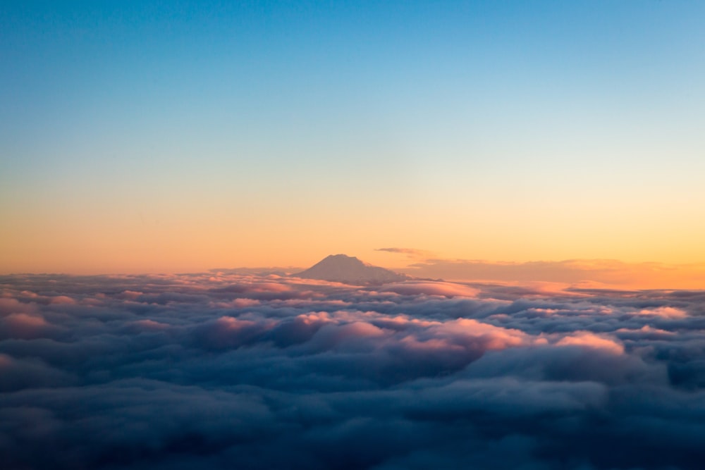 mountain over white clouds during daytime