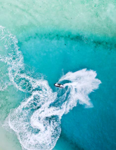 A vibrant jet ski cutting through turquoise Caribbean waters with Barbados coastline in the background.