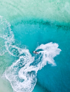 A vibrant jet ski speeding across the crystal-clear blue waters of Cancun with white sandy beaches in the background.