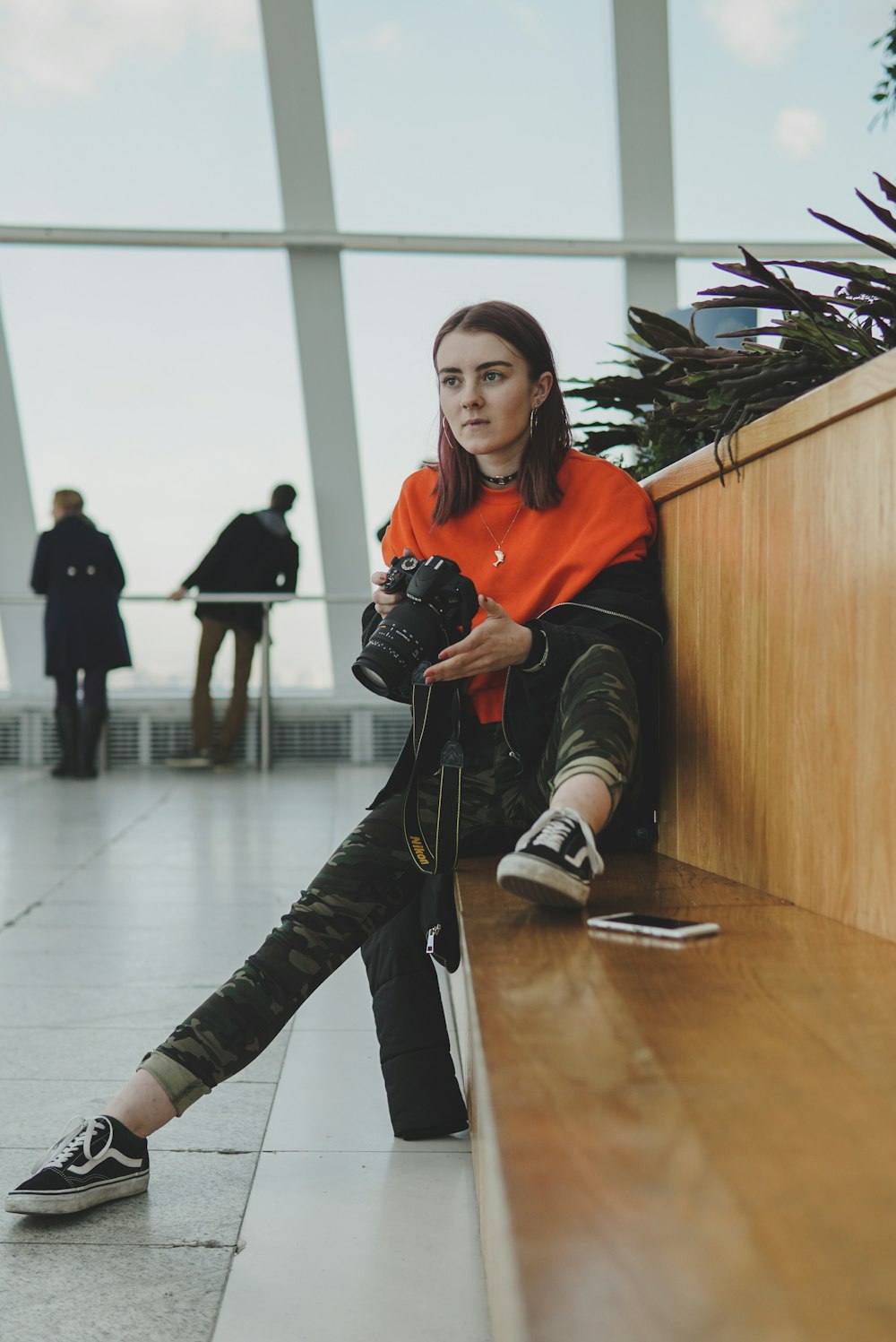 woman holding DSLR camera while sitting on chair