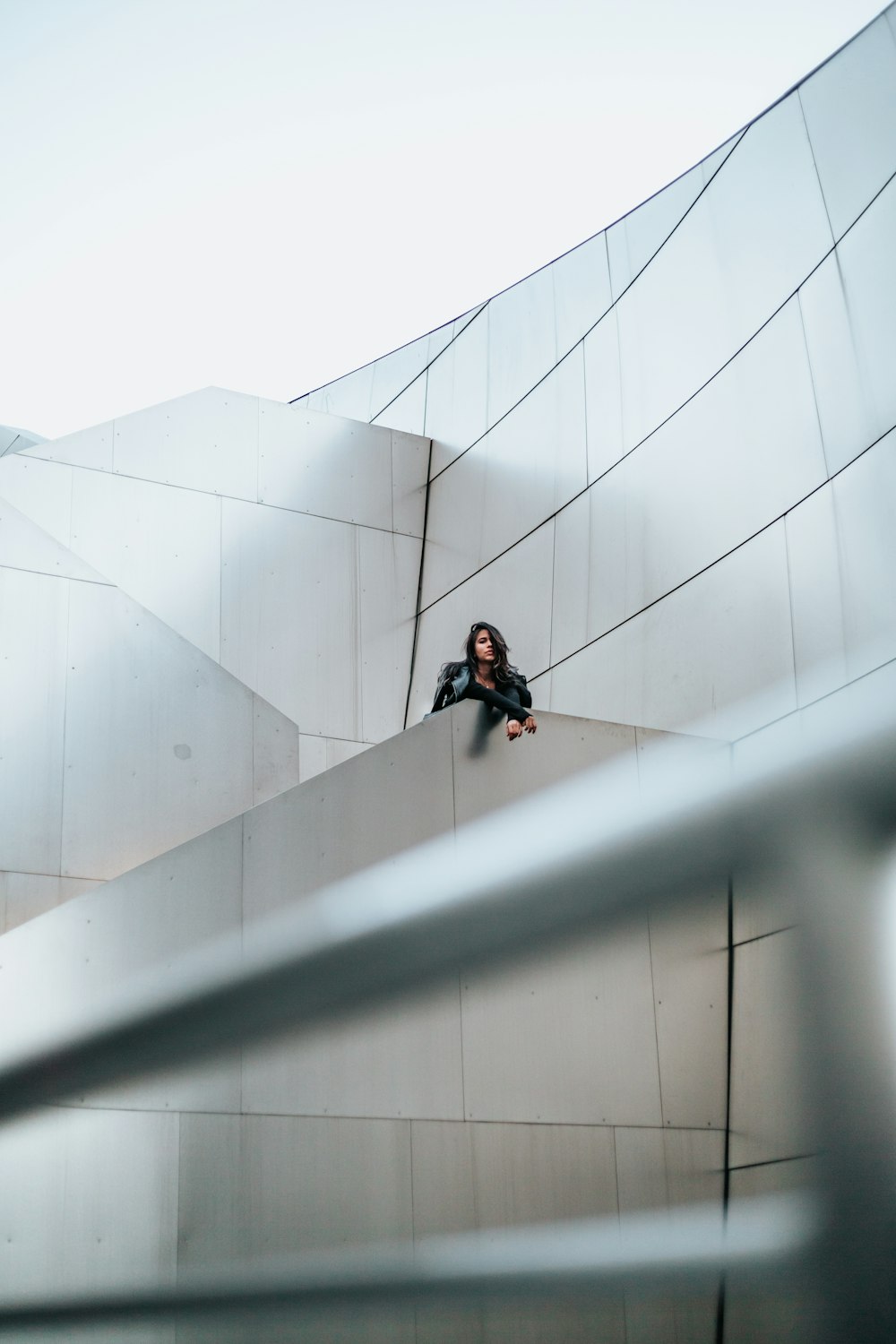 woman in black top leaning on grey wall