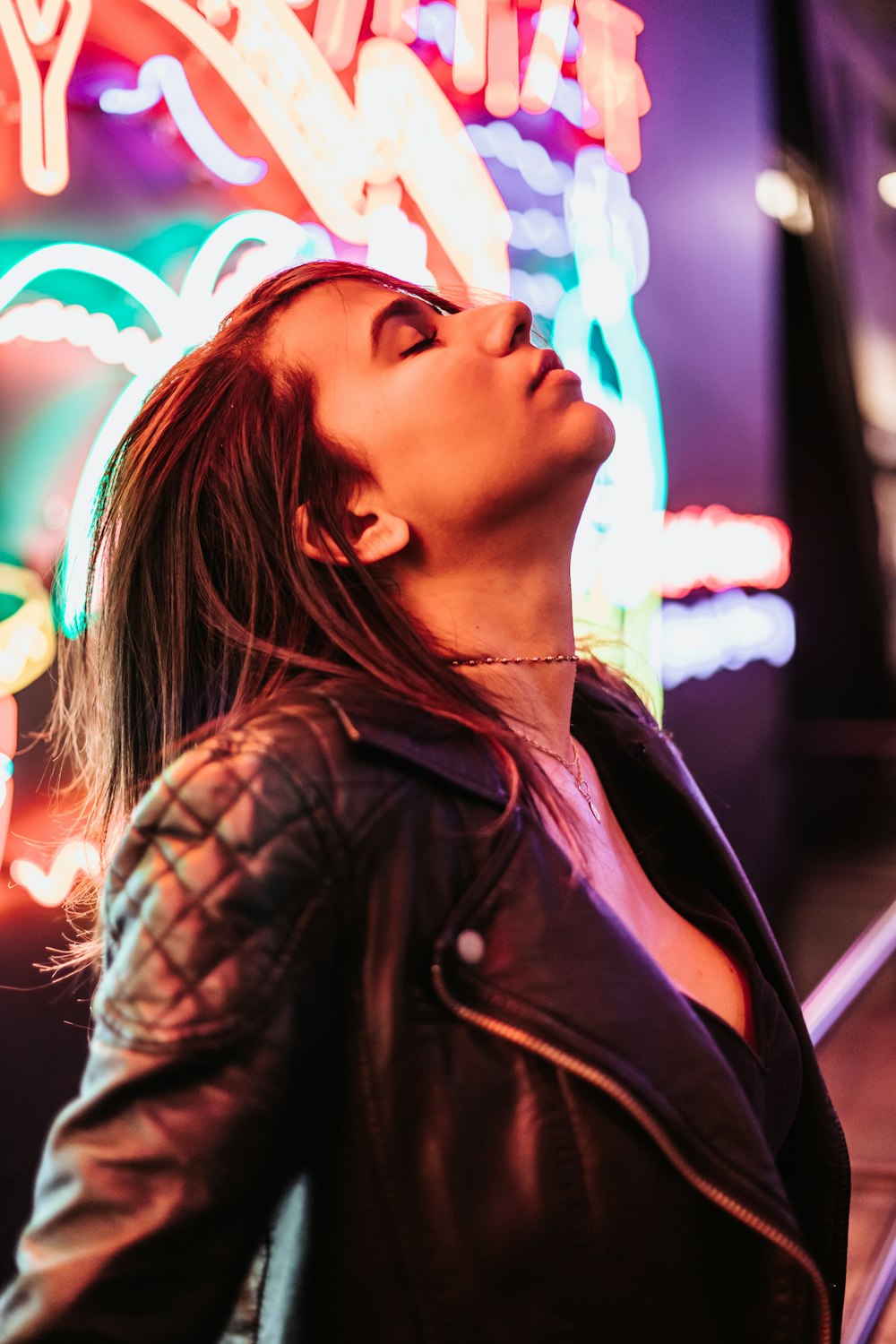woman wearing black leather jacket standing near neon signage