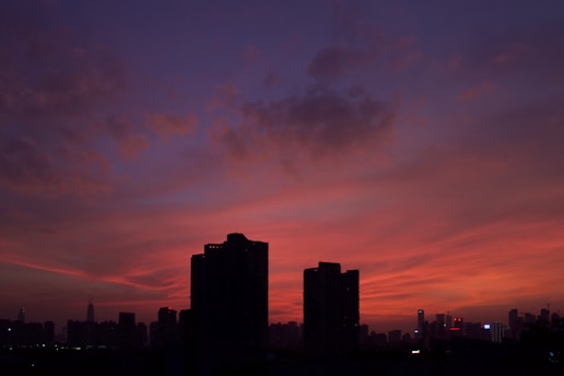 A vibrant cityscape at sunset with silhouettes of buildings and a colorful sky.