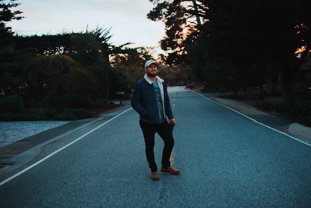 man standing at the center of road between trees