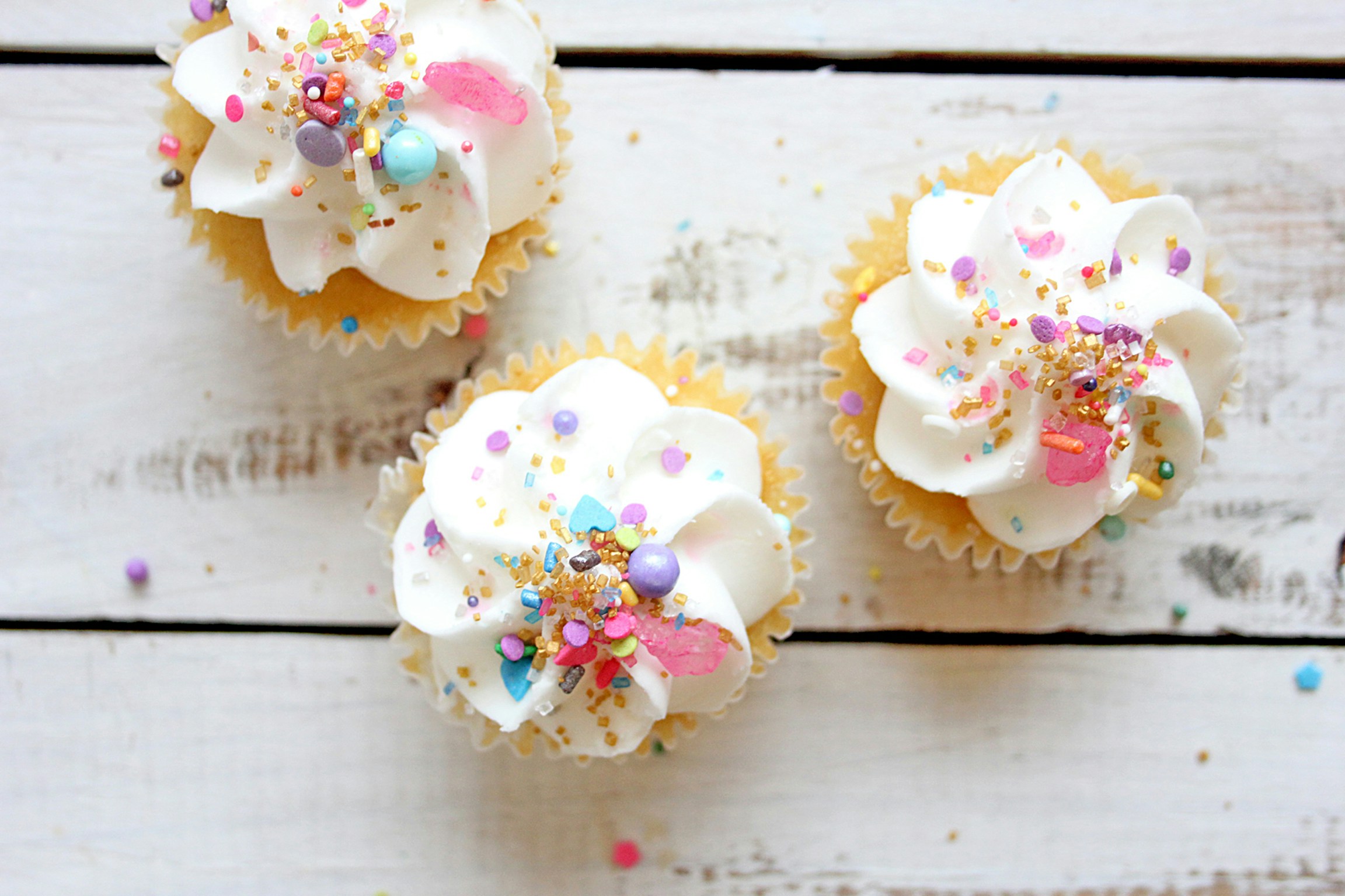Cupcakes with sprinkles on wooden background