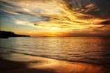 A serene beach at sunset with golden skies and calm waves