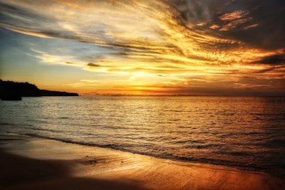 A serene beach at sunset with deep blue sea and golden sky reflecting the calmness of Thailand's coastal beauty.