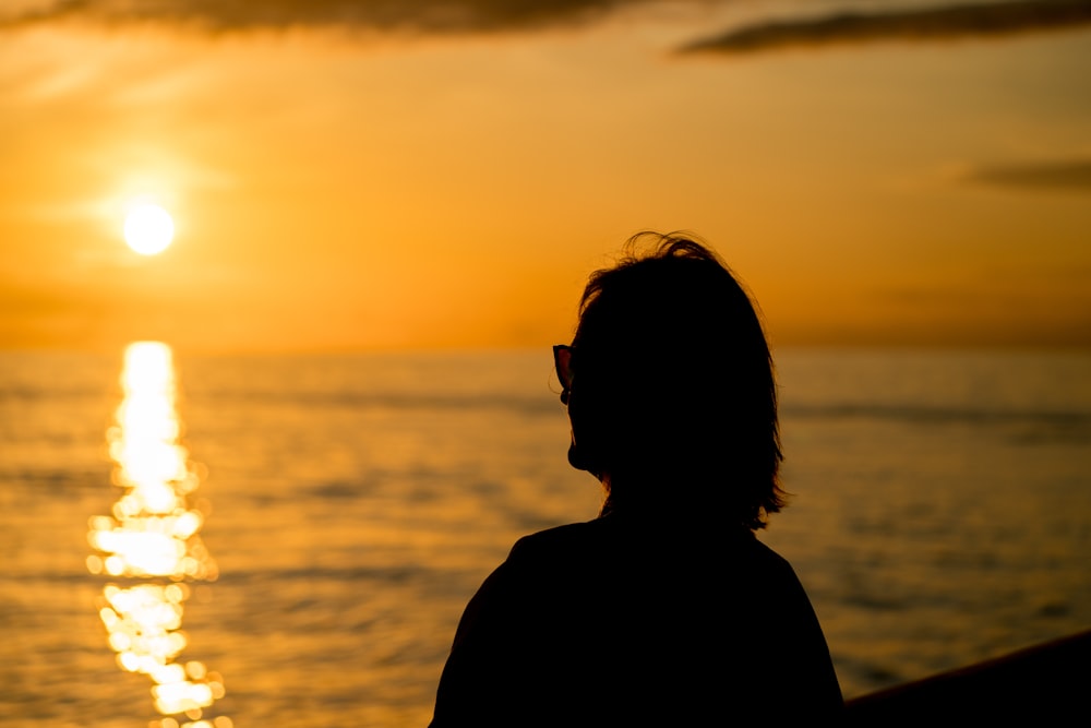 Silueta de mujer de pie frente a la puesta del sol
