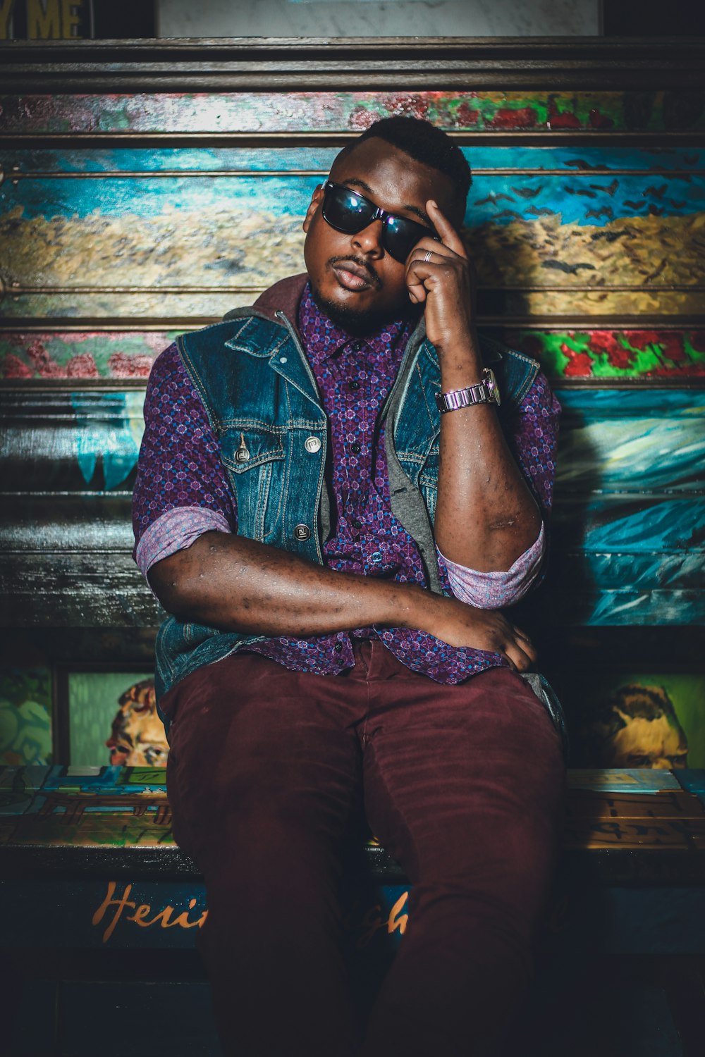 homme assis portant des lunettes de soleil appuyé sur un banc floral