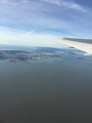 Aerial view of a cargo plane taking off over a coastal city.