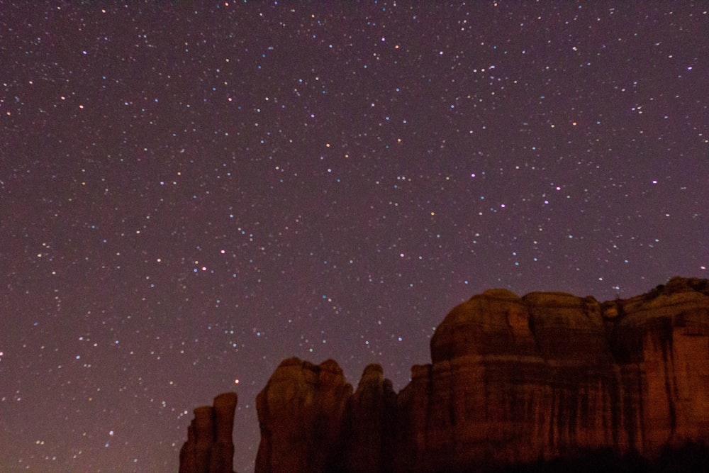 rock formation under gray sky with stars during night time