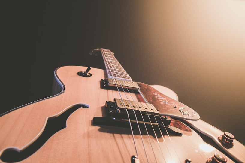 Close-up of a sleek bass guitar with rich wood grain and shiny strings under warm lighting.