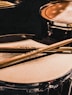 pair of brown wooden drumsticks on top of white and gray musical drum