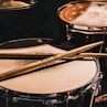 pair of brown wooden drumsticks on top of white and gray musical drum