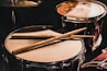 pair of brown wooden drumsticks on top of white and gray musical drum
