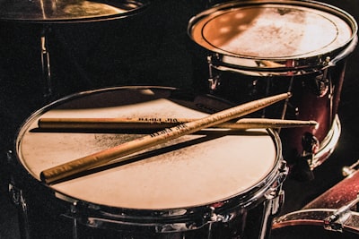 pair of brown wooden drumsticks on top of white and gray musical drum drumstick zoom background
