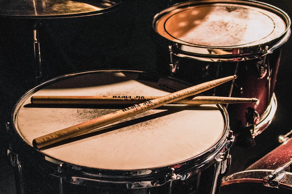 pair of brown wooden drumsticks on top of white and gray musical drum