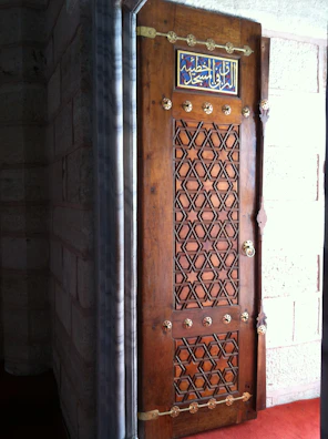 Close-up of a mosque’s ornate wooden door featuring traditional Islamic geometric patterns.