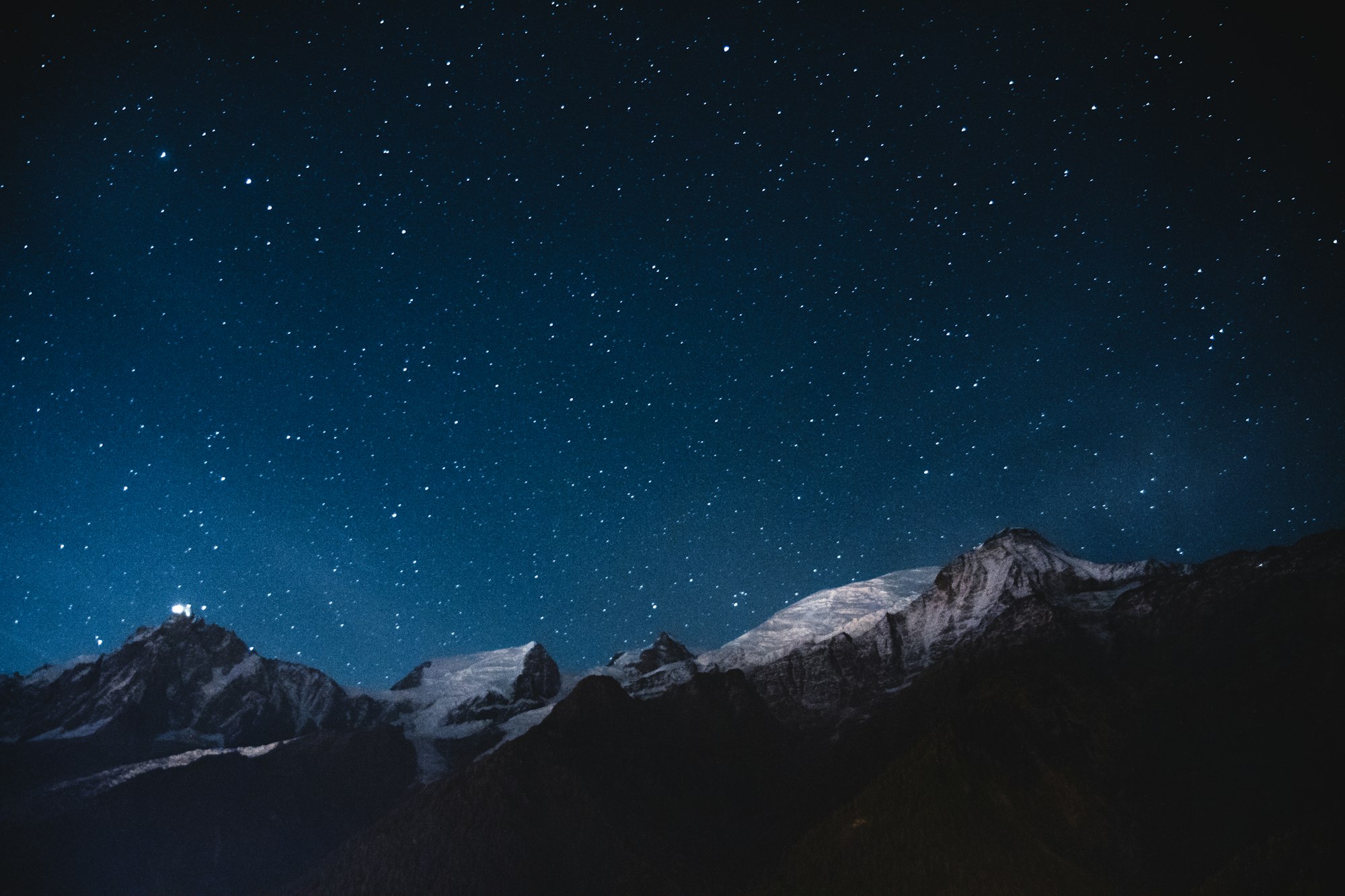 Snow-covered peaks under a starry night sky