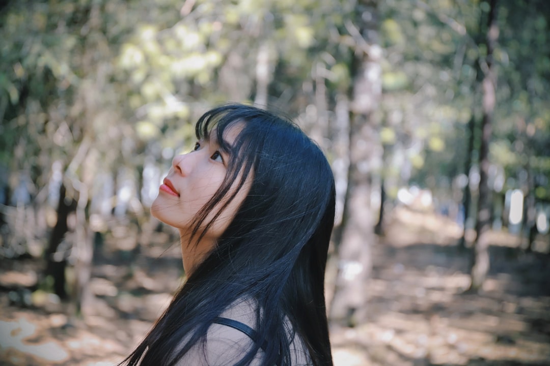 woman standing near trees looking up