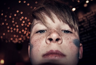 Close-up of a little girl with a sparkling princess face paint, eyes bright with delight.