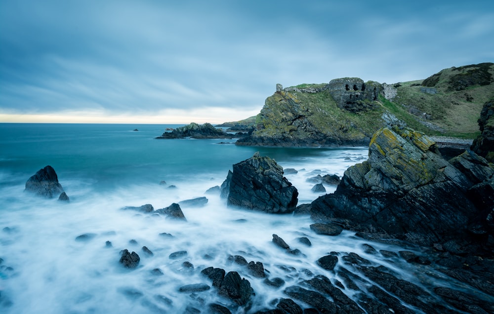 rock formation beside body of water during day time