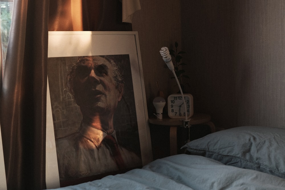 painting of man leaning against window beside bed