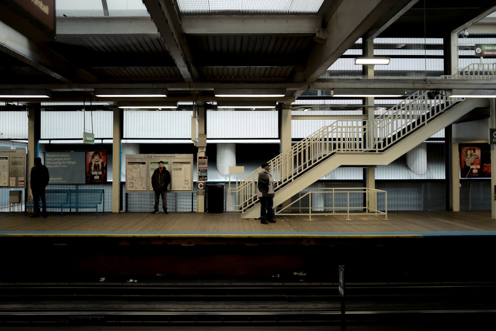 três pessoas esperando na estação de trem