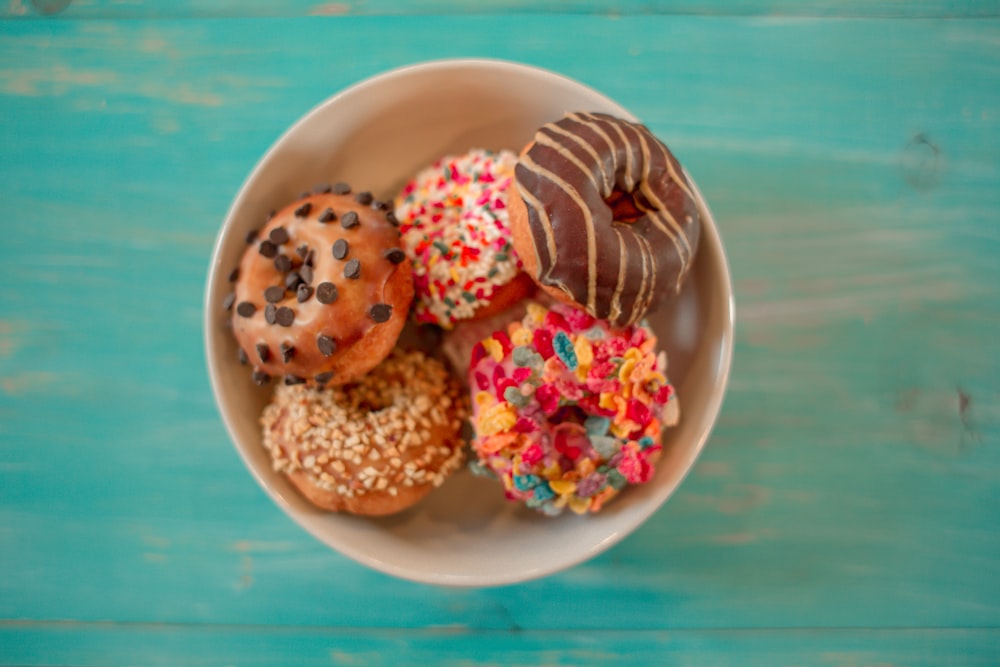 Sieben Donuts mit verschiedenen Geschmacksrichtungen auf brauner Keramikschale