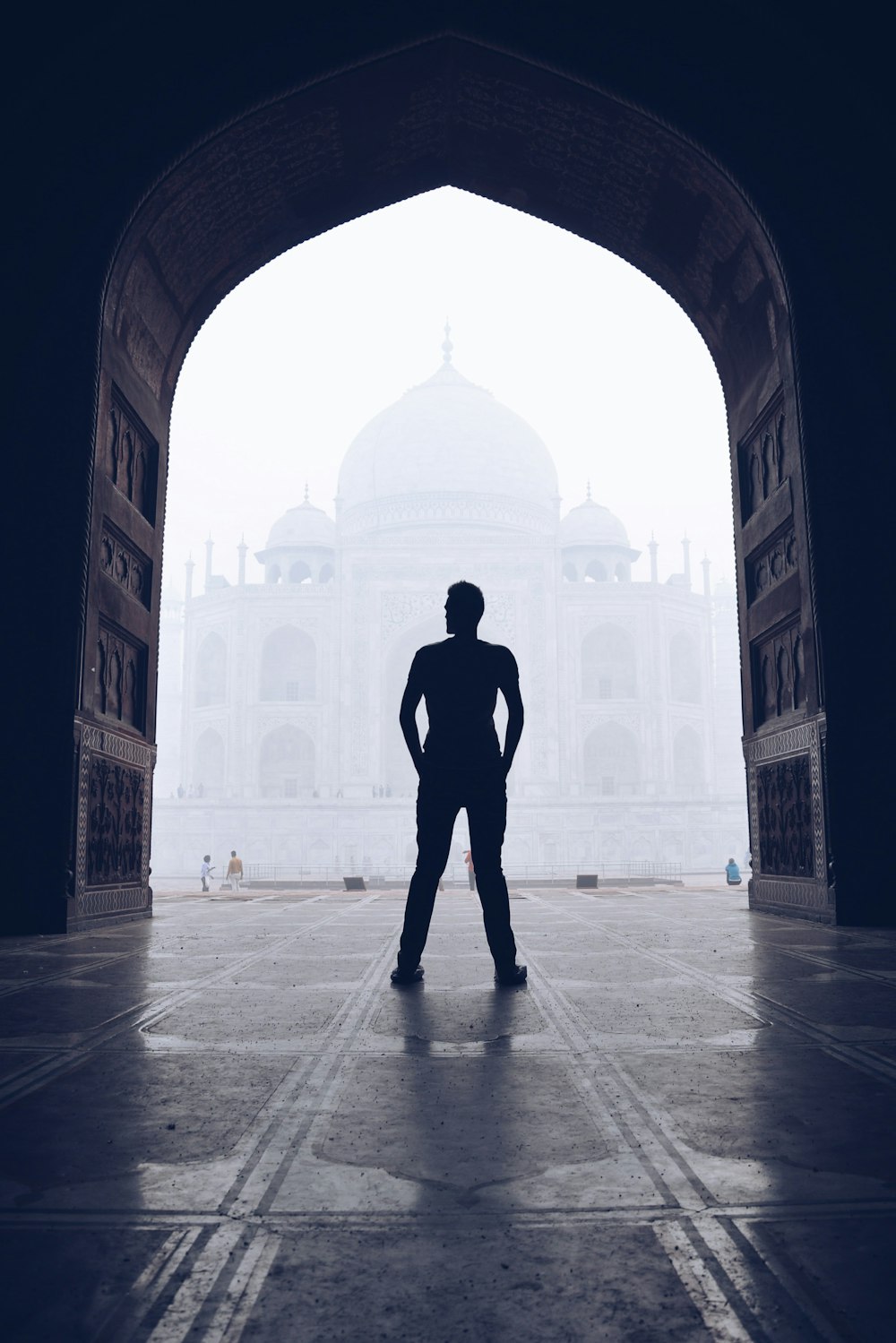 silhouette photography of man standing near door in front of mosque