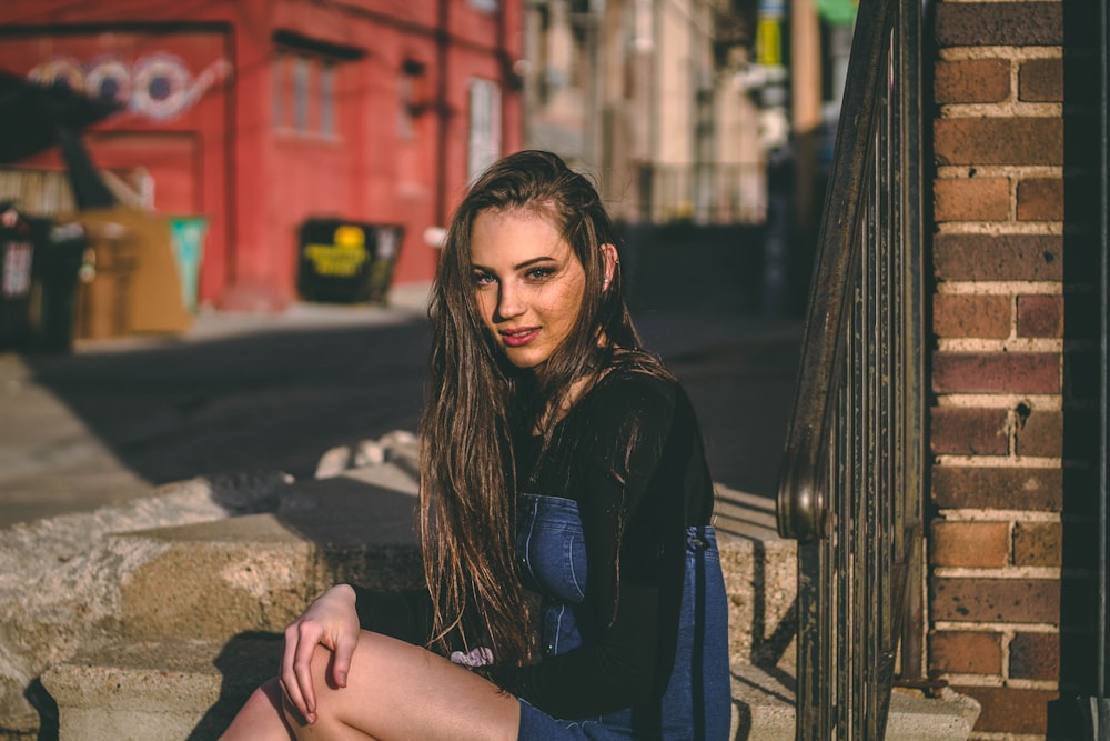 smiling woman sitting near brown brick wall during daytime