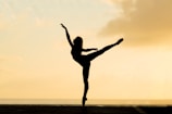 An elegant silhouette of a ballet dancer against a glowing sunset backdrop.