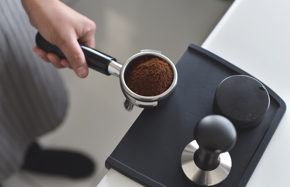 person holding pot with coffee powder