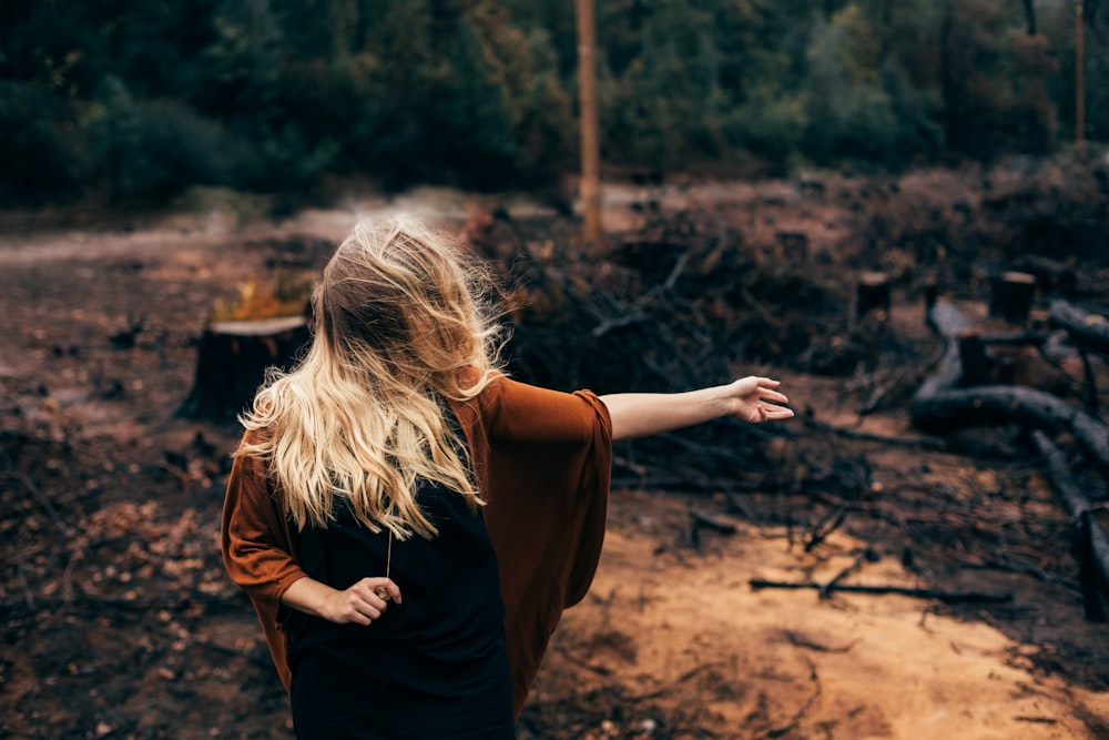 woman standing in front of burned and cut trees