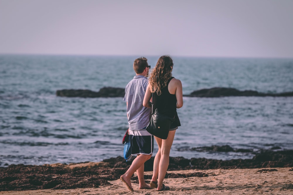 man and woman walking by the beach during daytime