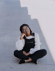 woman in overall pants sitting on pavement