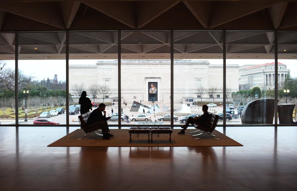 two people sitting on chairs in front of a large window