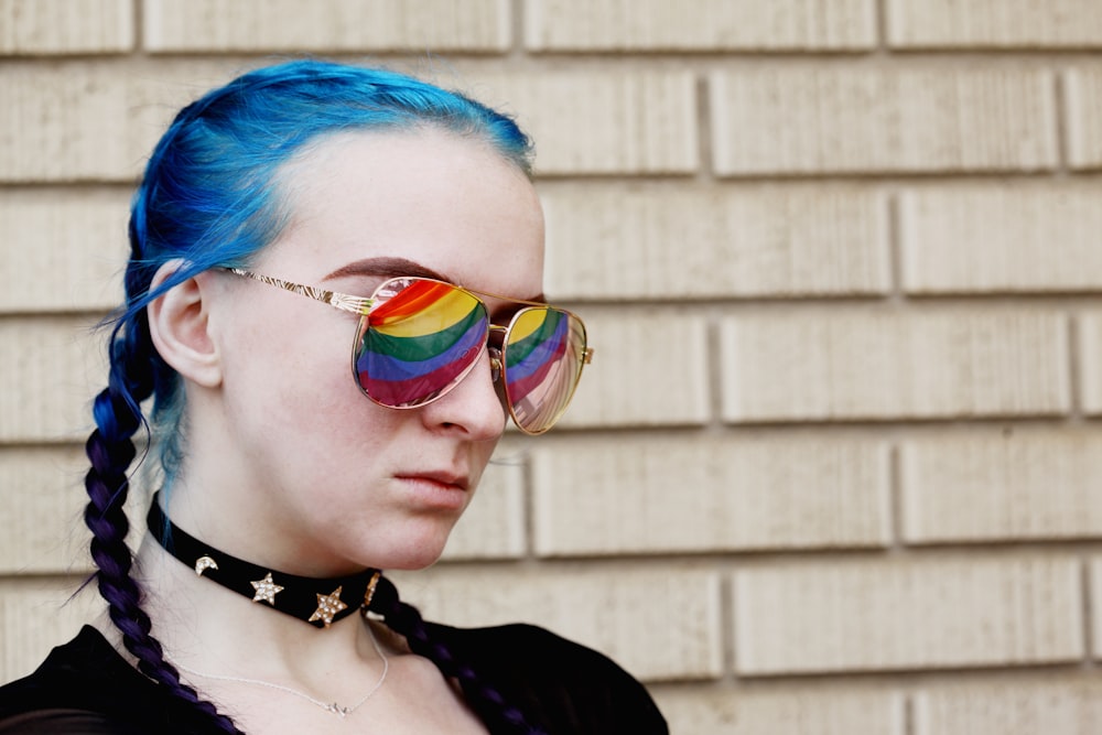 Una donna con i capelli blu e gli occhiali arcobaleno