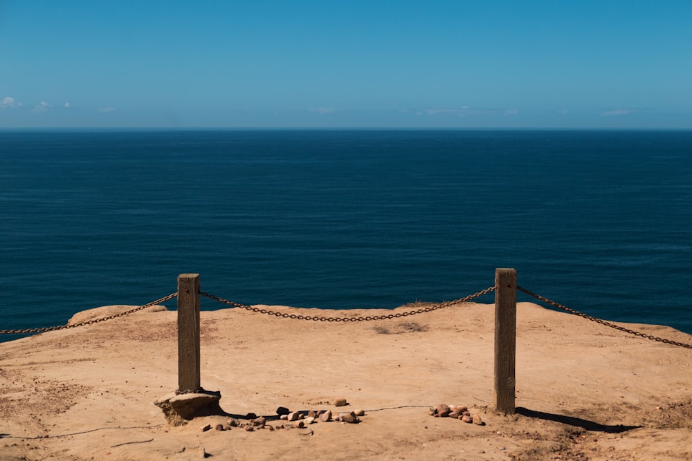 昼間、青い海の近くの茶色の砂浜に茶色の木製の支柱