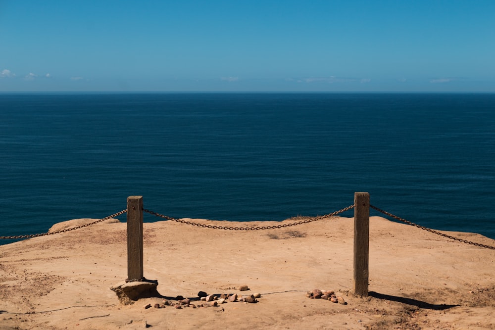 brown wooden post on brown sand near blue sea during daytime