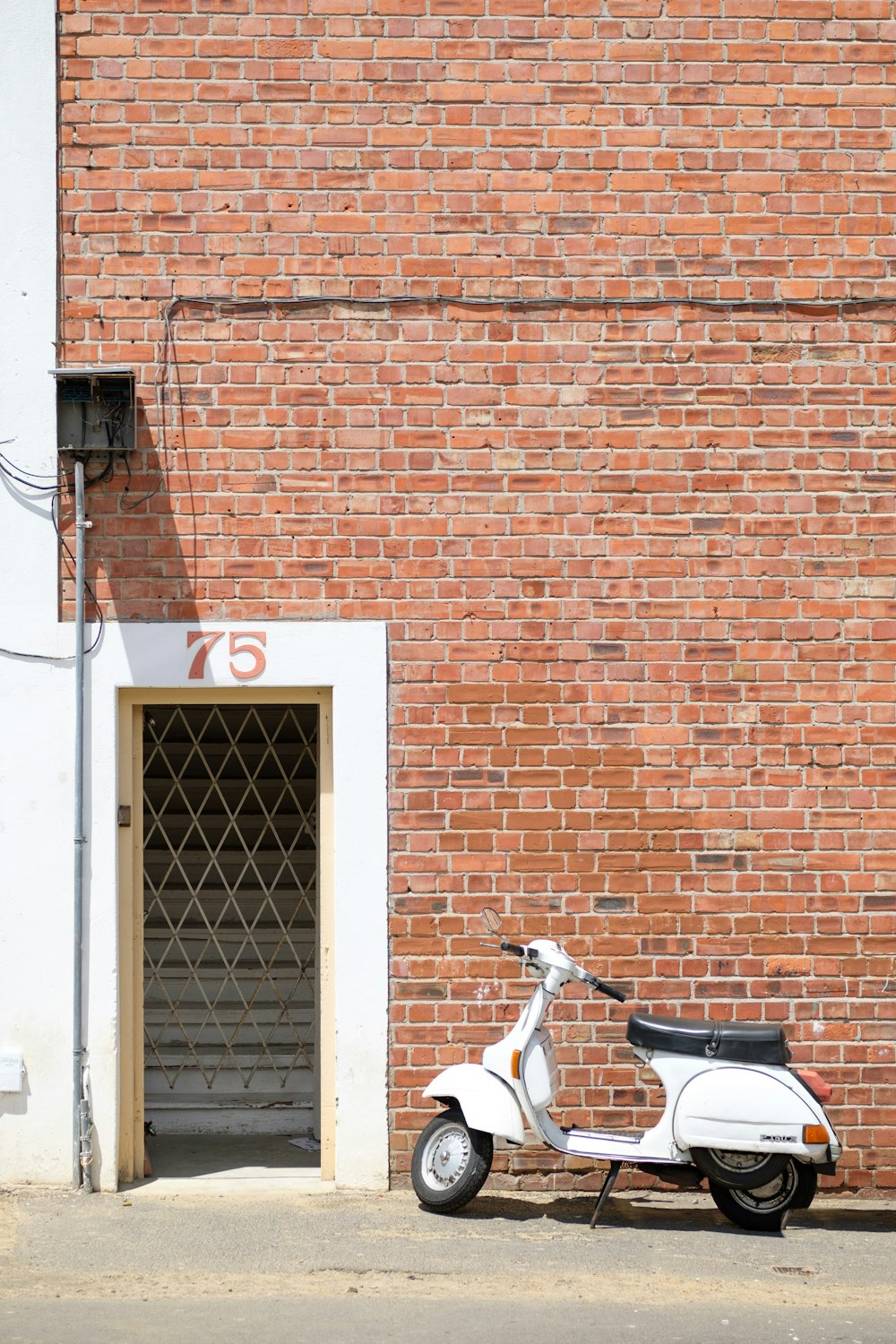 white motor scooter parked on street near brown building