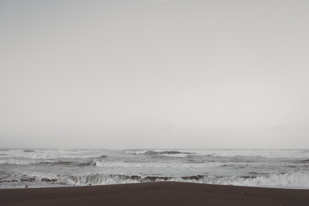 seawaves on seashore under cloudy skies